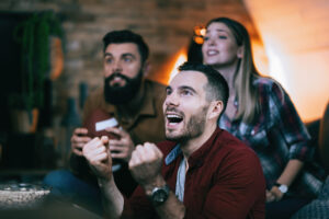 young-man-cheering-his-team-while-watching-sports-championship-with-friends-scaled.jpg